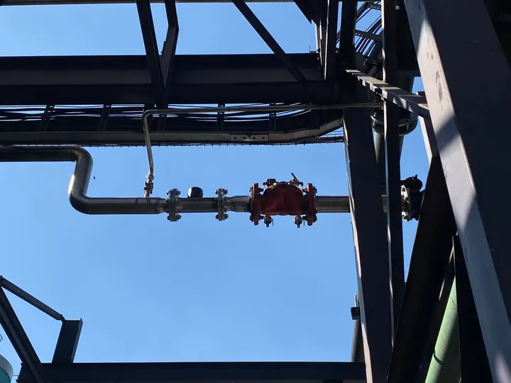 Elevated pipe run and in-line valve assembly within structural steelwork